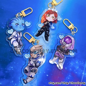 May include: Five acrylic keychains featuring cartoon characters with gold-colored clasps. The characters are in various poses and outfits, with blue, purple, and red color schemes. The keychains are on a blue background with the text "etsy.com/shop/chocolamay".