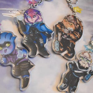 May include: A collection of colorful, cartoon-style character keychains. Each keychain features a unique character design with vibrant colors and details. The keychains are attached to silver chains with star-shaped charms.