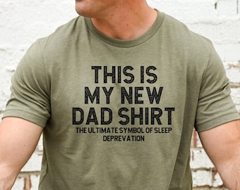 May include: A green t-shirt with the text "This is my new dad shirt. The ultimate symbol of sleep deprivation."