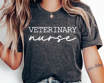 May include: A dark grey t-shirt with the text "VETERINARY nurse" in white lettering. The shirt is being worn by a person with long blonde hair.