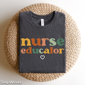 May include: Dark gray t-shirt with the text "nurse educator" in colorful retro-style letters and a small heart symbol.