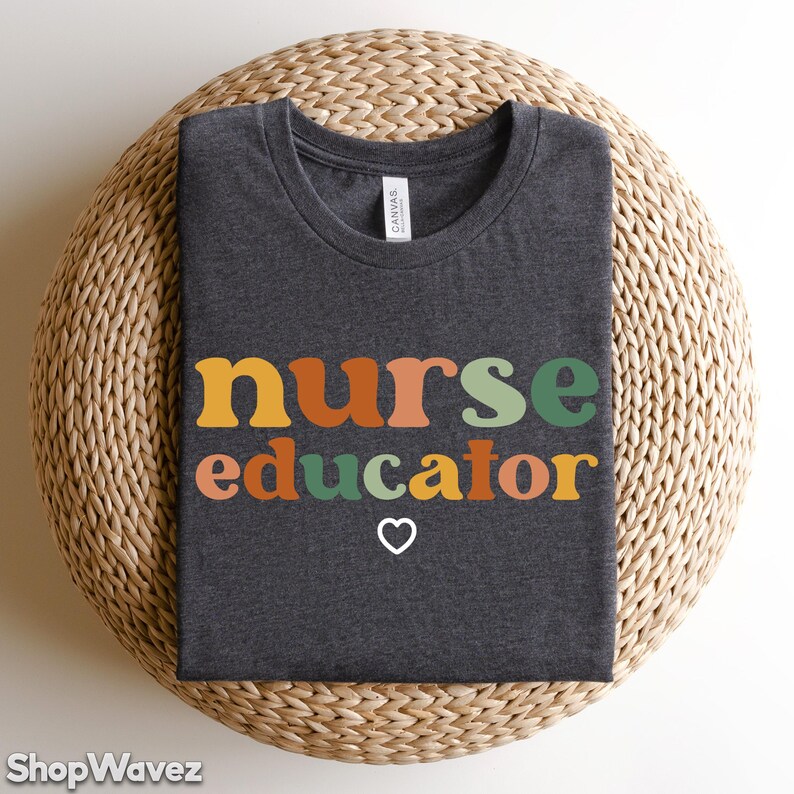 May include: Dark gray t-shirt with the text "nurse educator" in colorful retro-style letters and a small heart symbol.