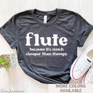 May include: Dark grey t-shirt with the word "flute" in large white letters. Below, the text reads "because it's much cheaper than therapy." White trainers with red trim are visible on the right.