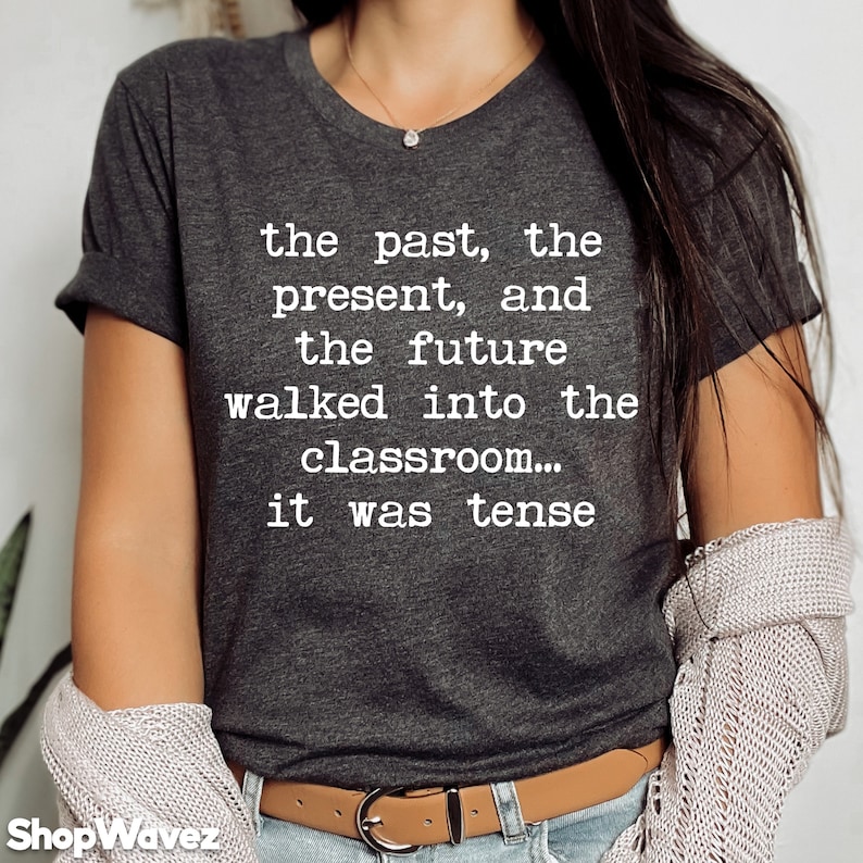 May include: A dark gray t-shirt with white text that reads "the past, the present, and the future walked into the classroom... it was tense".