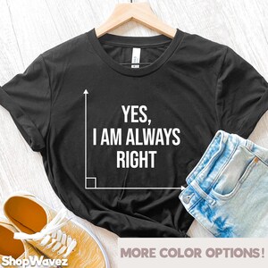 May include: Black t-shirt with white text that reads "YES, I AM ALWAYS RIGHT" and a white right angle graphic. The shirt is on a wooden surface with a pair of yellow trainers and blue jeans.