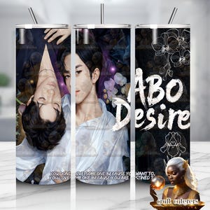 May include: A cylindrical tumbler featuring a digital illustration of two individuals with dark hair in white shirts, overlaid with the text ABO DESIRE and floral line art on a dark background. The design includes a quote at the bottom edge.