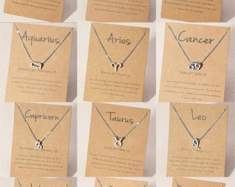 May include: Twelve cards with silver necklaces featuring zodiac signs and dates. Each card has a brown background with white text describing the zodiac sign.