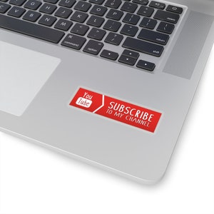 May include: Red sticker with a white YouTube logo and the text "SUBSCRIBE TO MY CHANNEL" on a silver laptop.