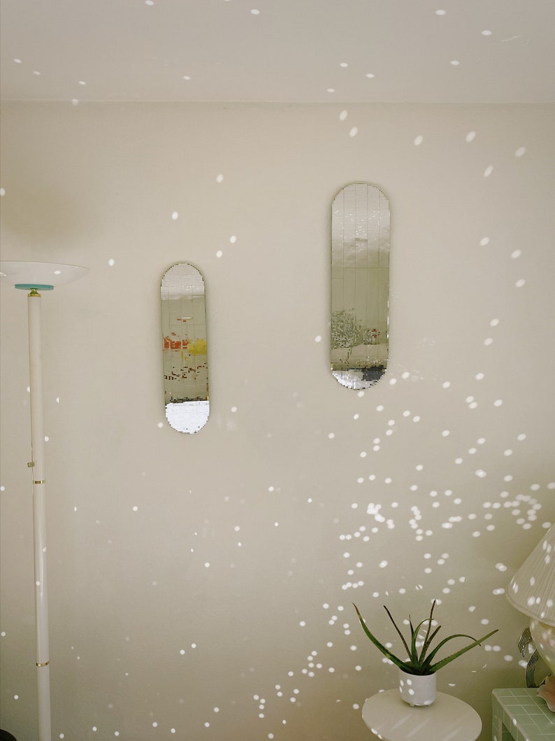 Puede incluir: Dos espejos rectangulares con un dise&ntilde;o de azulejos espejados cuelgan de una pared blanca. Los espejos est&aacute;n colocados verticalmente y est&aacute;n ligeramente desplazados uno del otro. La pared est&aacute; cubierta de peque&ntilde;os puntos redondos blancos.