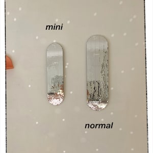 Puede incluir: Dos espejos de mosaico plateado, uno etiquetado como "mini" y el otro como "normal".