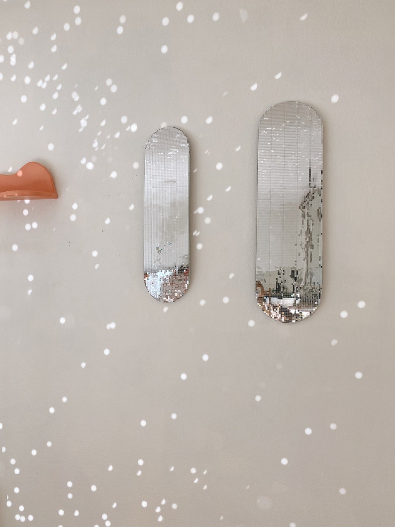 Puede incluir: Dos espejos ovalados plateados con un dise&ntilde;o de mosaico est&aacute;n montados en una pared de color beige claro. La pared tiene un patr&oacute;n de peque&ntilde;os puntos blancos.