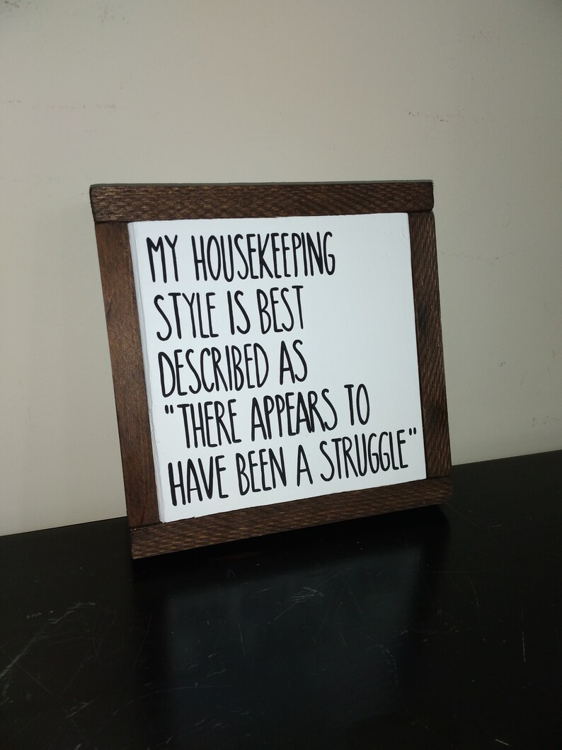 Puede incluir: Un letrero de madera con el texto "MY HOUSEKEEPING STYLE IS BEST DESCRIBED AS "THERE APPEARS TO HAVE BEEN A STRUGGLE""