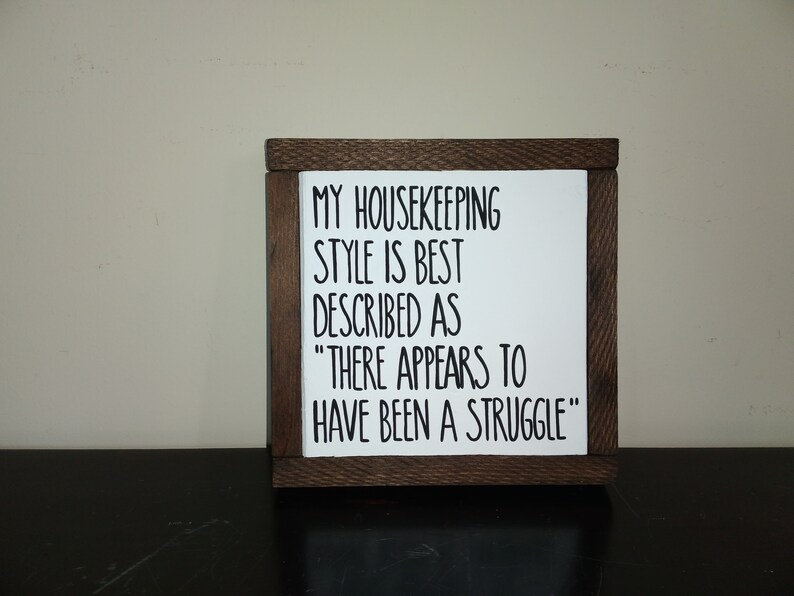 Puede incluir: Un letrero de madera con el texto "MY HOUSEKEEPING STYLE IS BEST DESCRIBED AS "THERE APPEARS TO HAVE BEEN A STRUGGLE""