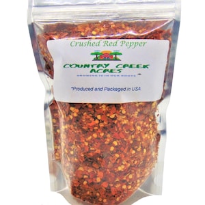 May include: A resealable bag of crushed red pepper flakes. The bag is labeled "Crushed Red Pepper" and "Country Creek Acres" with the tagline "Growing is in our roots." The bag also states "Produced and Packaged in USA."