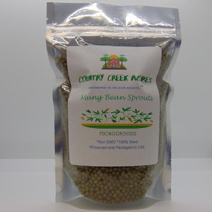 May include: A silver resealable bag filled with mung bean sprouts. The bag has a white label with the text "COUNTRY CREEK ACRES", "GROWING IS IN OUR ROOTS", "Mung Bean Sprouts", "MICROGREENS", "*Non GMO *100% Seed", and "*Produced and Packaged in USA".