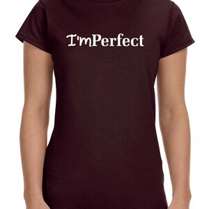 May include: A maroon t-shirt with the text "I'm Perfect" in white.