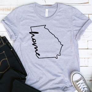 May include: Gray t-shirt with a black outline of the state of Georgia and the word "home" written inside the outline.
