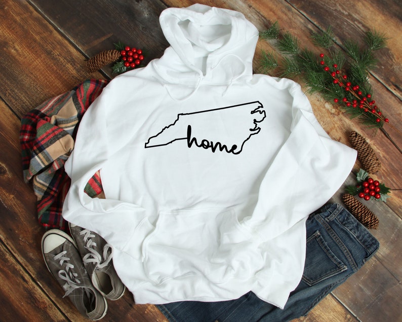 May include: White hooded sweatshirt with a black outline of the state of North Carolina and the word "home" written in cursive.