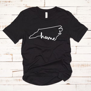 May include: Black t-shirt with a white outline of the state of North Carolina and the word "home" written inside the outline.