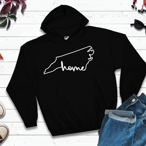 May include: Black hooded sweatshirt with a white outline of the state of North Carolina and the word "home" written inside the outline.