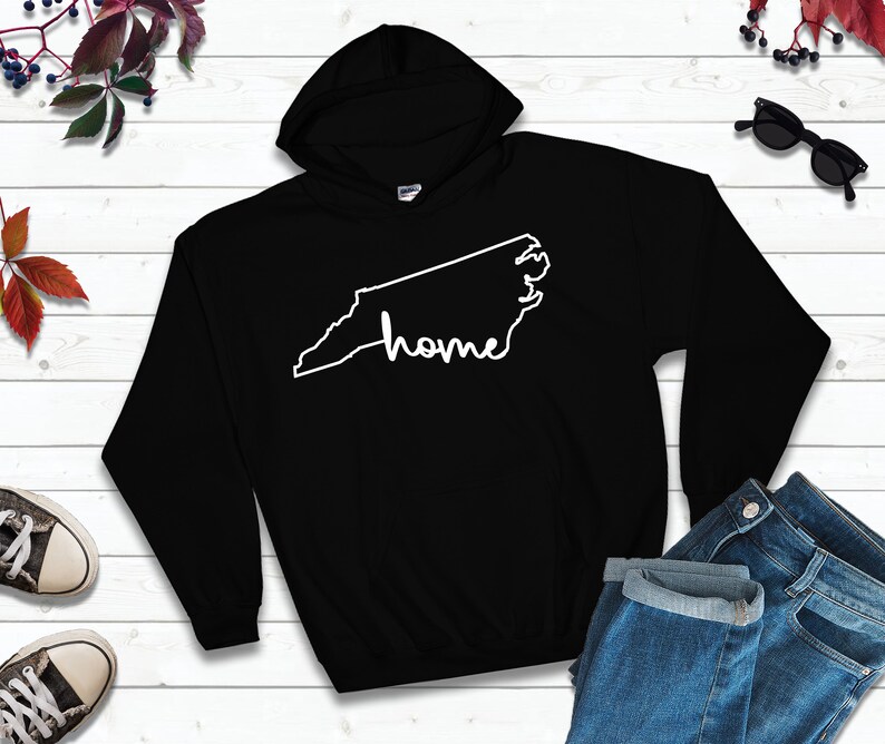 May include: Black hooded sweatshirt with a white outline of the state of North Carolina and the word "home" written inside the outline.