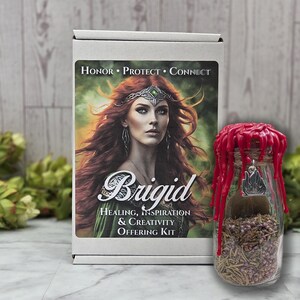 May include: A white box with the text "Honor Protect Connect" and the name "Brigid" with the words "Healing, Inspiration & Creativity Offering Kit". A glass jar with a red wax seal and a silver charm is next to the box.