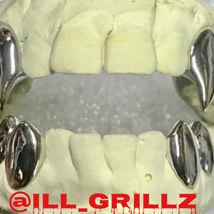 May include: Silver grillz with pointed teeth, designed to fit over the front teeth. The grillz are shown on a white mold of a mouth. The text "@ILL_GRILLZ" is visible at the bottom of the image.