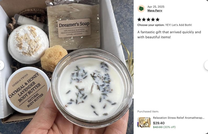 May include: A gift box containing a candle, soap, bath bomb, body butter, and a natural sponge. The candle is in a glass jar and has lavender buds. The soap is labeled "Dreamer's Soap". The body butter is labeled "Oatmeal & Honey Lavender Body Butter".