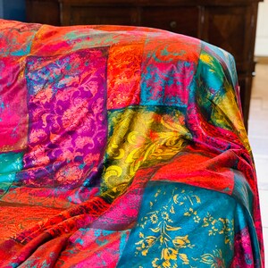 May include: A colorful patchwork throw blanket with a vibrant mix of red, pink, yellow, blue, and green hues. The blanket features a variety of floral and paisley patterns.