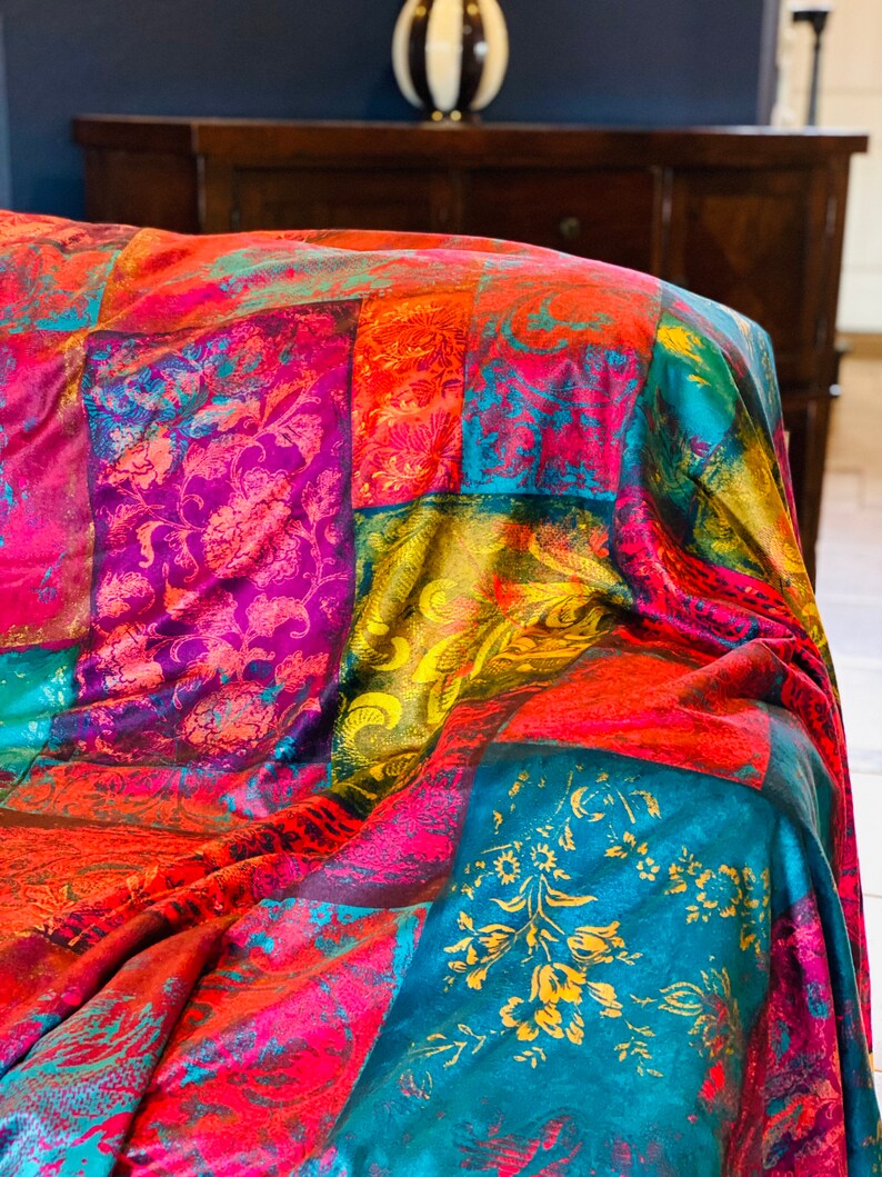 May include: A colorful patchwork throw blanket with a vibrant mix of red, pink, yellow, blue, and green hues. The blanket features a variety of floral and paisley patterns.