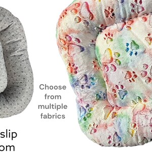 May include: Two dog beds, one with a gray and white polka dot pattern and a non-slip bottom, and the other with a white background and colorful paw prints. Choose from multiple fabrics.