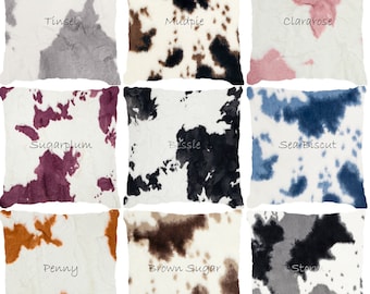 Può includere: Nove cuscini decorativi con stampa di mucca in diversi colori. I colori includono: Tinsel (grigio), Mudpie (marrone e bianco), Clararose (rosa), Sugarplum (viola), Bessie (nero e bianco), Sea Biscuit (blu), Penny (arancione), Brown Sugar (marrone) e Storm (grigio).