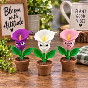 May include: Three potted calla lily figurines in purple, white, and pink, each featuring a grumpy facial expression with large eyes and a furrowed brow. The plants have green leaves and yellow spadices, sitting in small brown pots.