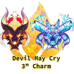 Może przedstawiać: Para charmów Devil May Cry o rozmiarze 7,6 cm, jeden z czerwoną i czarną głową demona, a drugi z niebieską i białą głową demona.