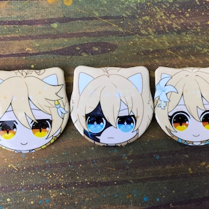 May include: Three round pins with cartoon characters. Each pin features a blonde character with cat ears and a different facial expression. The first pin has a character with a happy expression and yellow eyes. The second pin has a character with a neutral expression and blue eyes. The third pin has a character with a happy expression and orange eyes.