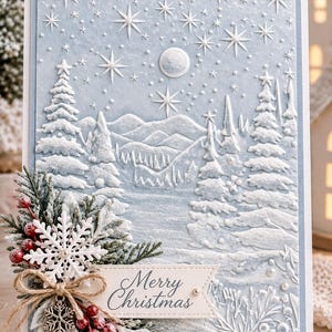 May include: A light blue greeting card featuring an embossed winter landscape with snow-covered pine trees, mountains, and a starry sky. A decorative cluster of faux greenery, red berries, and white snowflakes is attached with twine, including a tag reading Merry Christmas.