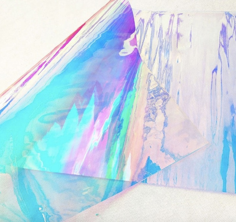 Pu&ograve; includere: Materiale olografico iridescente con uno spettro di colori tra cui blu, rosa e verde. Il materiale &egrave; stratificato, creando un senso di profondit&agrave; e dimensione. L'effetto complessivo &egrave; scintillante ed etereo.
