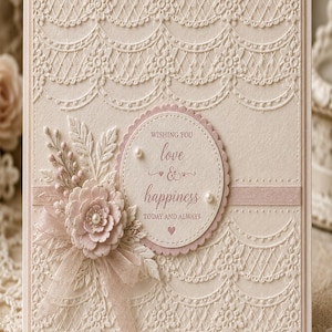 Peut inclure: Carte de vœux crème avec des détails complexes en forme de dentelle et une décoration florale. La carte présente un ruban rose, un motif circulaire avec l'inscription "Wishing you love & happiness" et de petites perles.