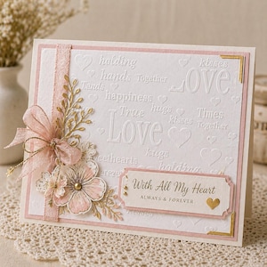 Könnte beinhalten: Eine handgefertigte Grußkarte mit weißem Hintergrund und rosa Akzenten. Die Karte zeigt geprägte Wörter wie "Love" und "Together", eine rosa Schleife und ein Blumenarrangement. Der Text "With All My Heart" ist ebenfalls sichtbar.