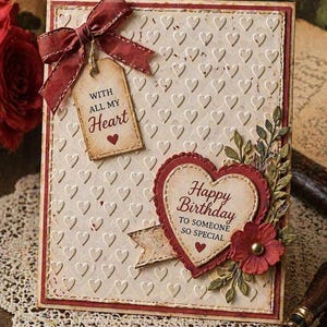 Puede incluir: Una tarjeta de cumpleaños hecha a mano con un fondo crema en relieve con forma de corazón. La tarjeta presenta un lazo rojo, una etiqueta que dice "With All My Heart" y un adorno en forma de corazón con las palabras "Happy Birthday to Someone So Special."