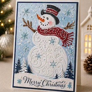 Könnte beinhalten: Handgefertigte Weihnachtskarte mit einem Schneemann-Design. Der Schneemann hat einen schwarzen Zylinder, eine orangefarbene Karottennase und einen roten Schal. Die Karte ist mit Schneeflocken und dem Schriftzug "Merry Christmas" verziert.