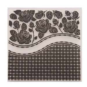 Op de afbeelding: Een doorzichtige, vierkante embossing folder met een bloemenrozenontwerp en een geweven mandpatroon. De rozen zijn gedetailleerd met bladeren en stelen, en het mandenpatroon bevindt zich in de onderste helft. Knutselgereedschap.