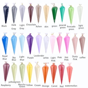 May include: A collection of colorful piping bags filled with various shades of frosting. Colors include black, gray, blue, pink, green, and more. Each bag is labeled with its color name, such as "Chocolate," "Raspberry," and "Orange."