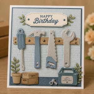 May include: A handmade birthday card with a light blue brick background. The card features a banner that says "Happy Birthday". Below the banner are tools, including a screwdriver, hammer, saw, and wrench. A toolbox says "You nail it every time!"