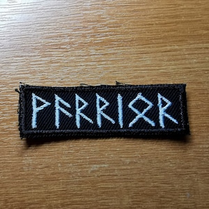 May include: Black fabric patch with white embroidered runes spelling "WARRIOR".