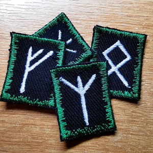 Broderade lappar med vikingarunor, mörk jadegrön kant och vita runor i flerfärgad färg