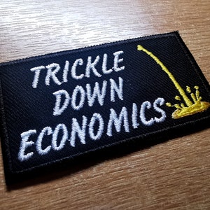 May include: Black embroidered patch with white text that reads "Trickle Down Economics" and a yellow graphic of a dripping faucet.