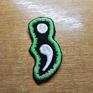 May include: Green and black embroidered patch with a white semicolon symbol.