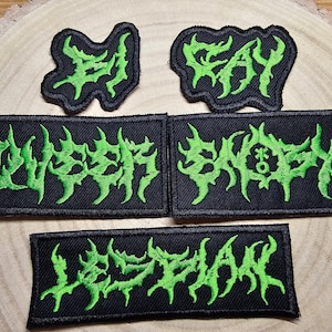May include: Four black and green embroidered patches with the words "Elysian", "Gay", "Slaughter", and "Lyskam" in a gothic font.