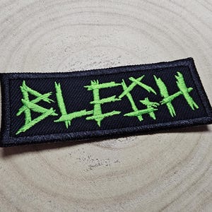 May include: Black and green embroidered patch with the word "BLEGH" in a stylized font.